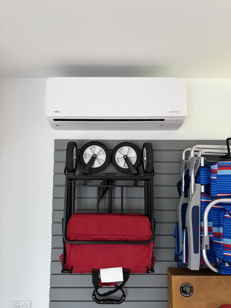 Indoor mini-split unit mounted above storage in a garage